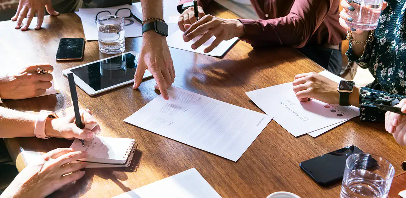 group of people at a table pointing at paper