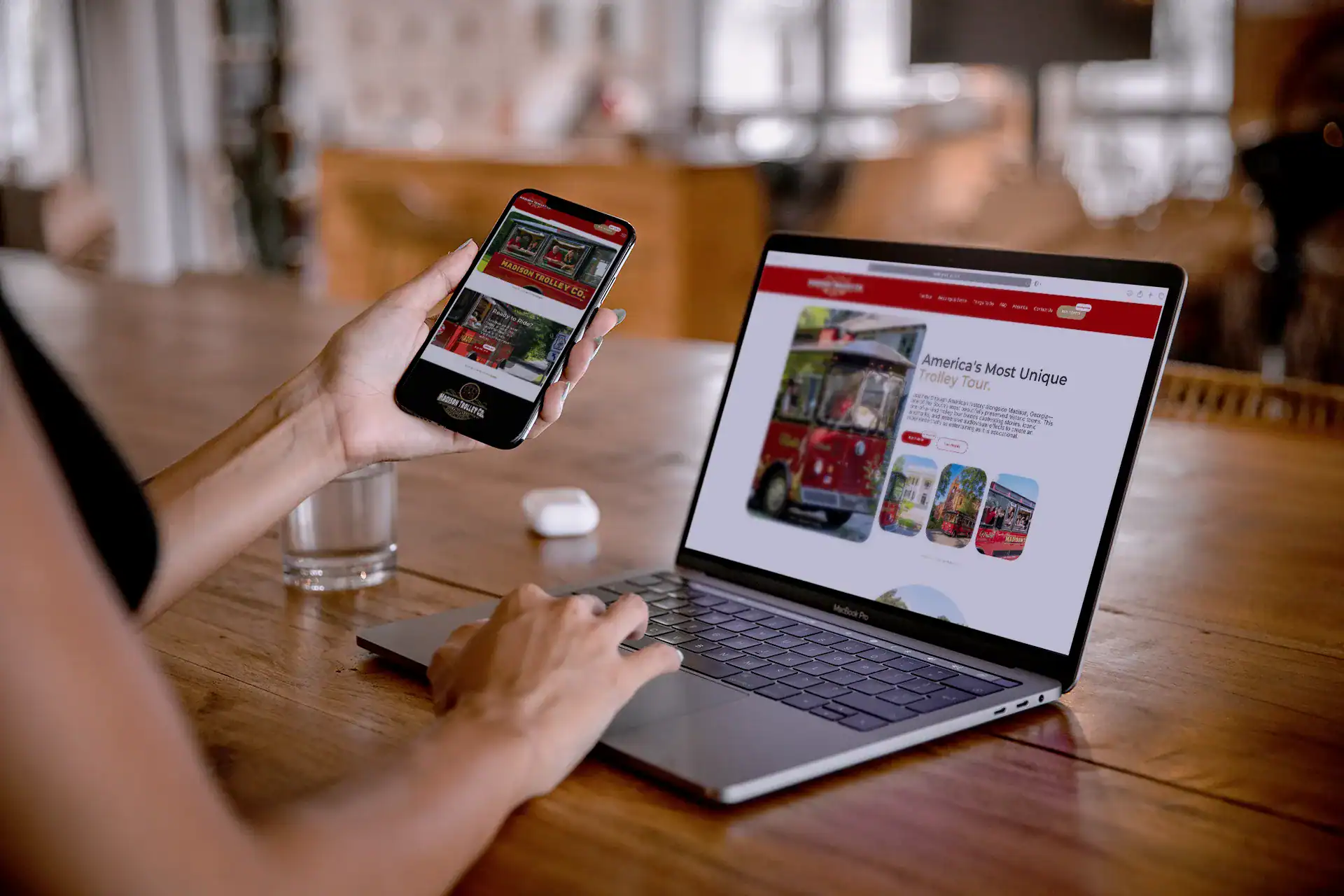 Mobile view of Seventy Seven Collective website with a person browsing regarding trolley tours on smartphone and laptop.